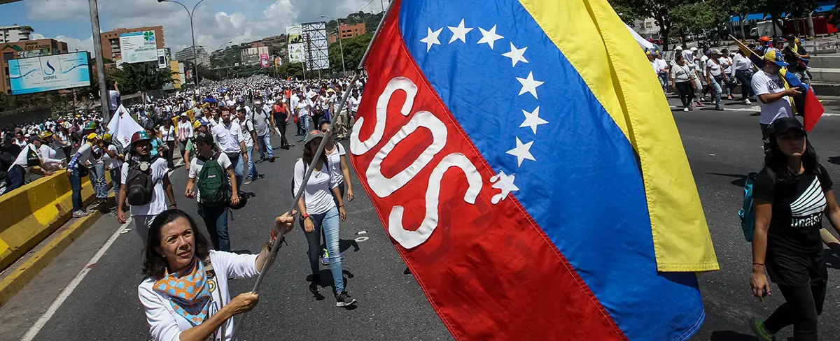 Protestante Pede Socorro Escrevendo SOS na Bandeira da Venezuela