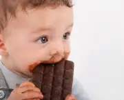Portrait of an adorable baby boy eating a plate of chocolate.